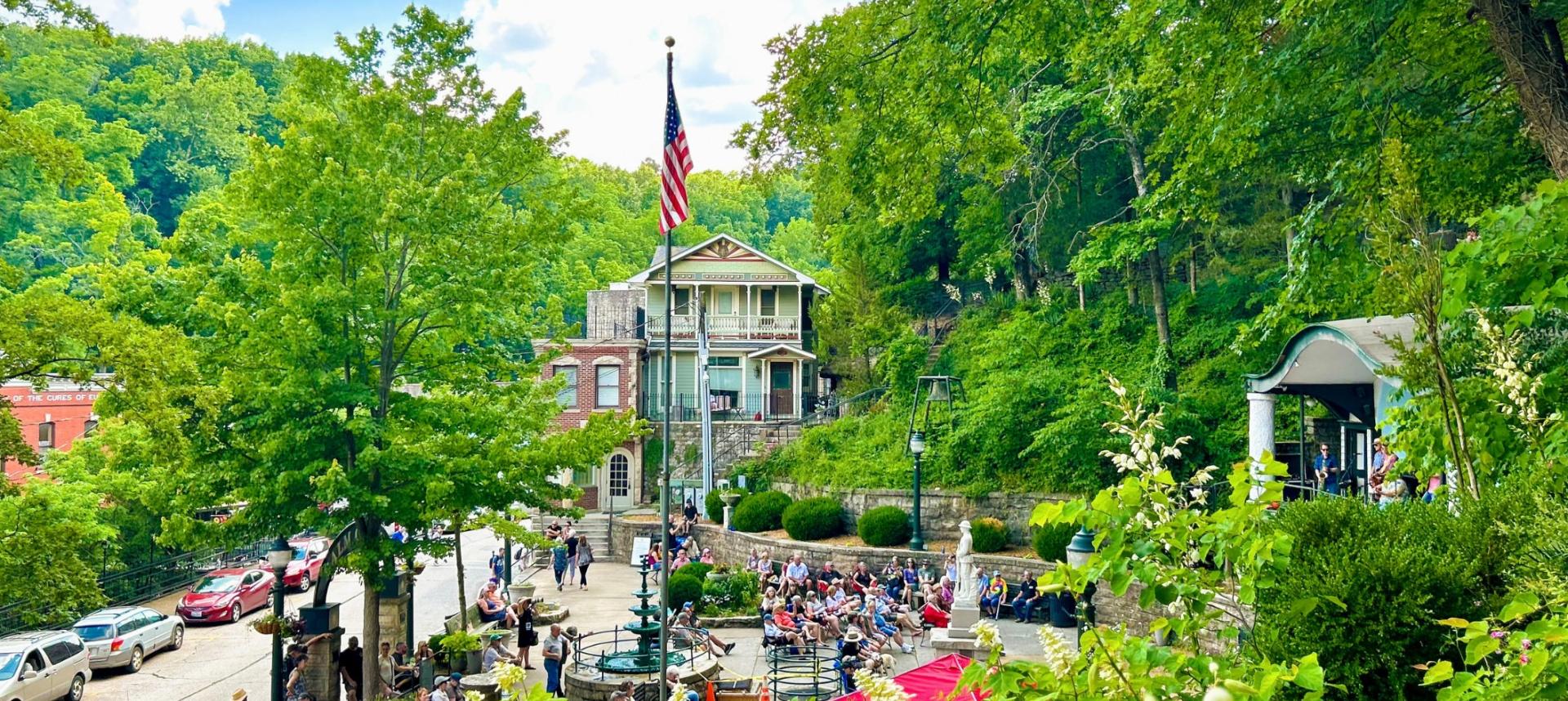 A view from street level of downtown Eureka Springs surrounded in lush green foliage.