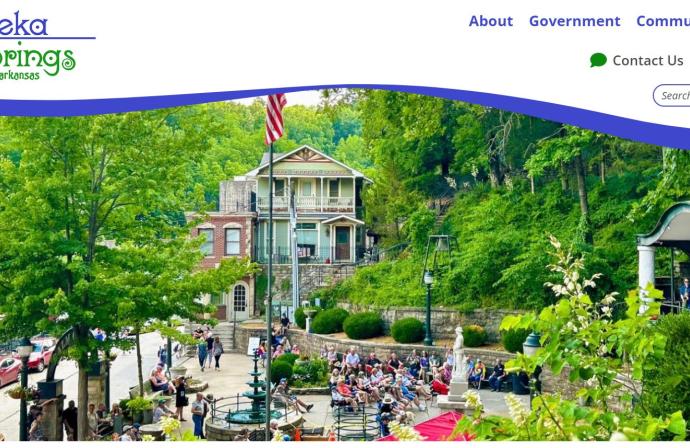 New Eureka Springs, Arkansas website with text and icons in royal blue and kelly green colors. An image of Downtown Eureka surrounded in lush green foliage.